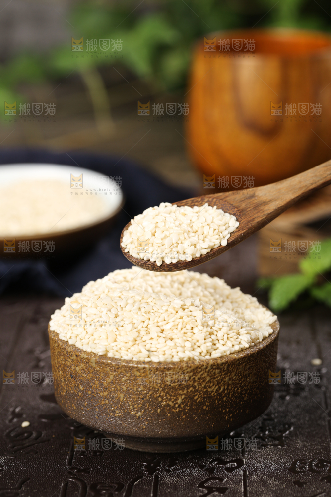 黑底上放着一碗东北芝麻和勺子上挖着芝麻