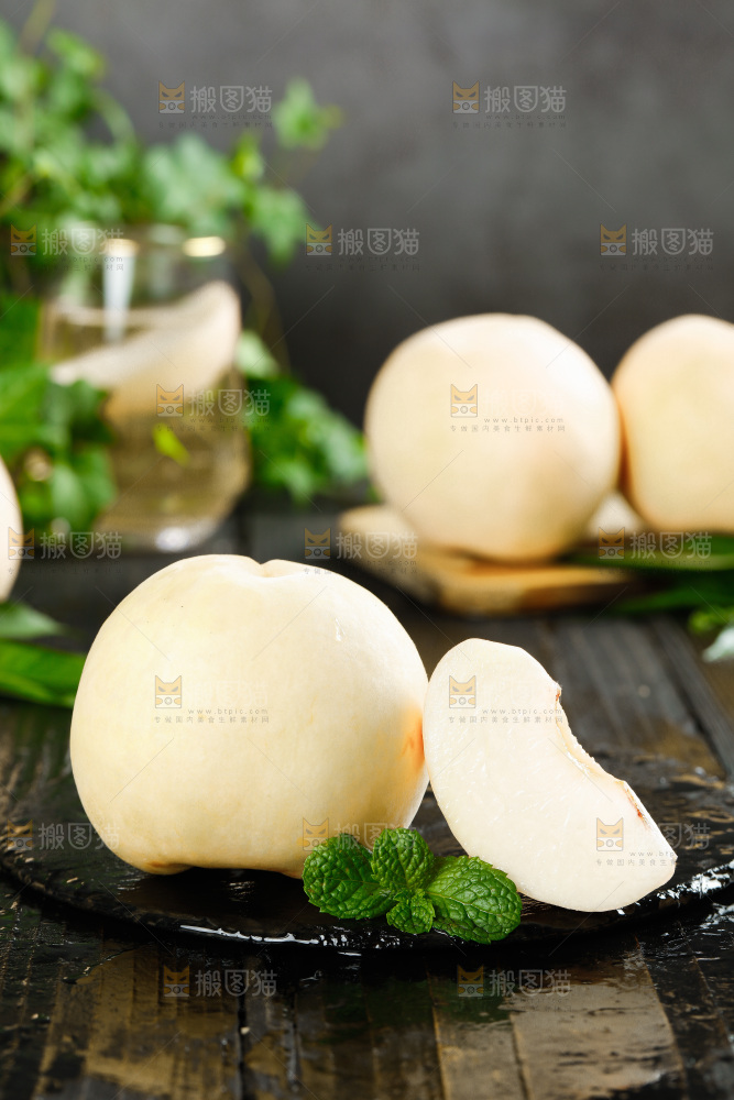 黑石板上放着白桃和切块的桃子果肉