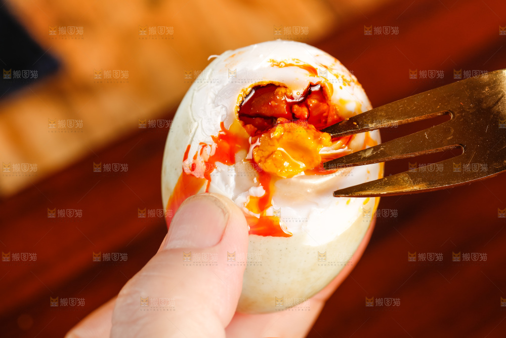 木板上手拿流油的海鸭蛋