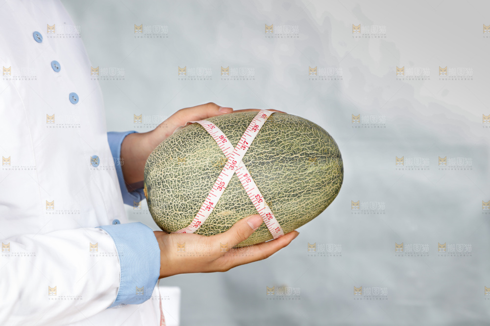 手里正在测量哈蜜瓜