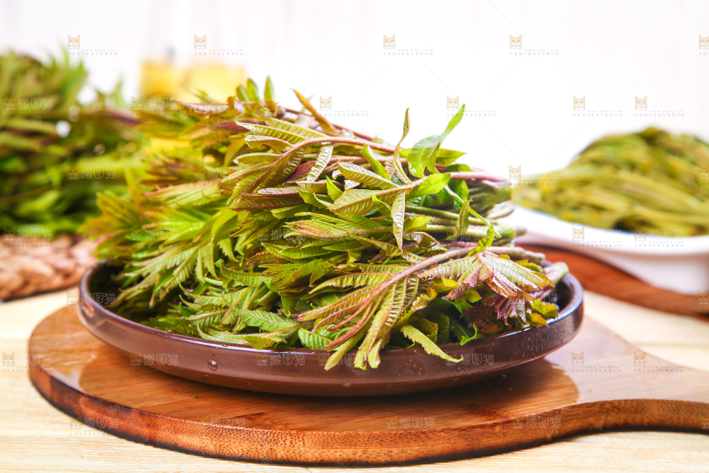 一盘香椿芽放在木底上