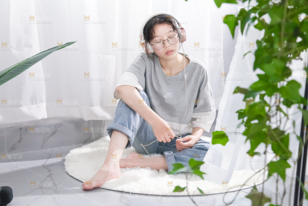 毛毯上坐着一位带耳机的女孩