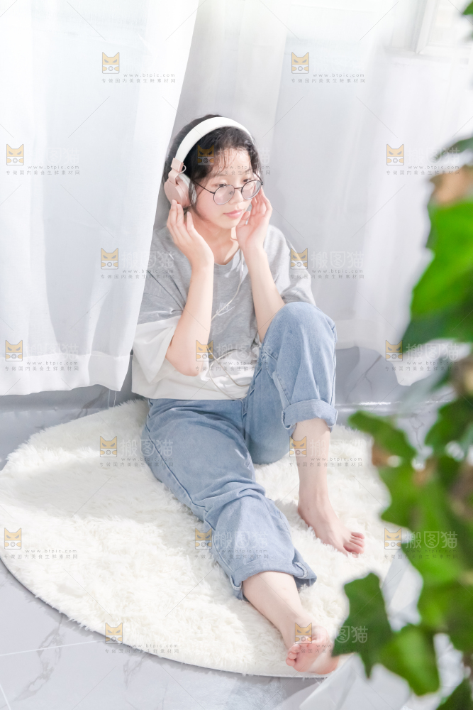 毛毯上坐着一位带耳机的女孩
