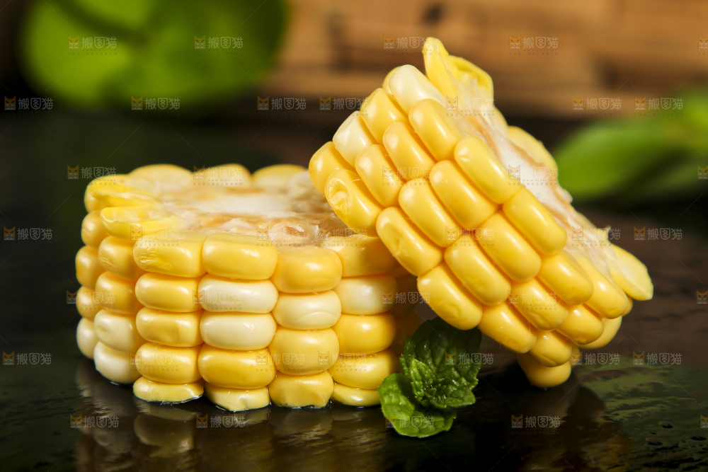 黑石板上放着掰开的甜玉米