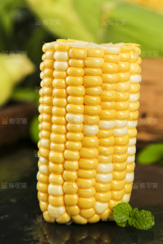 黑石板上放着掰开的甜玉米