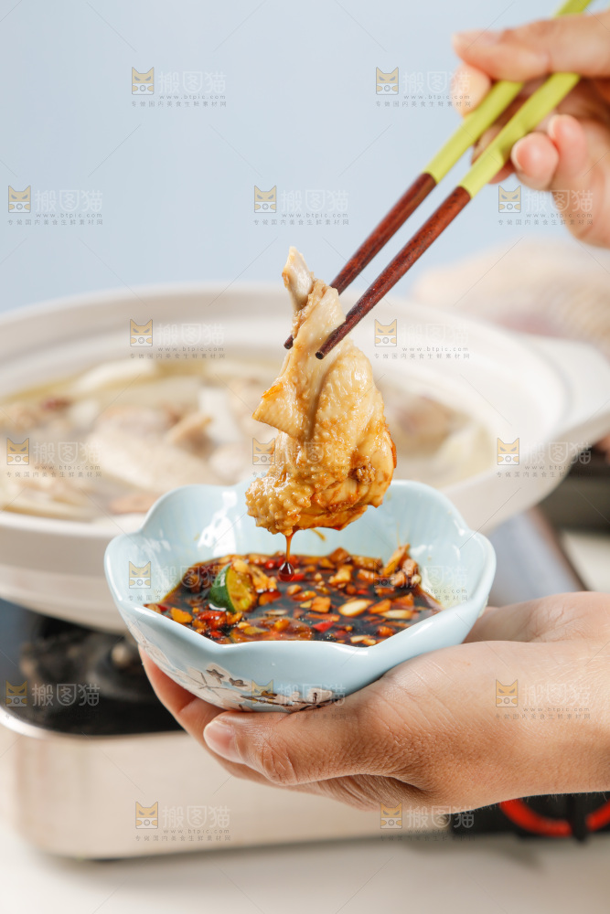 筷子上夹着蘸汁的椰子鸡