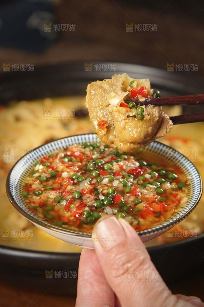 筷子上夹着蘸酱的鸡肉