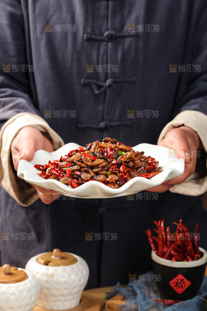 手里端着一盘爆炒蚕蛹