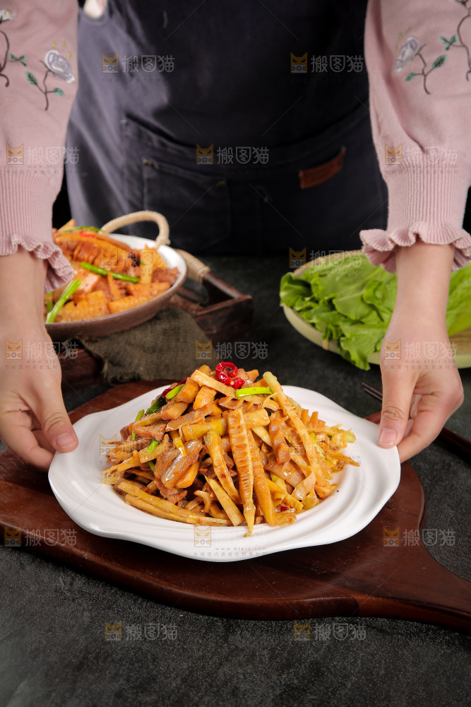 手里端着一盘竹笋烧肉