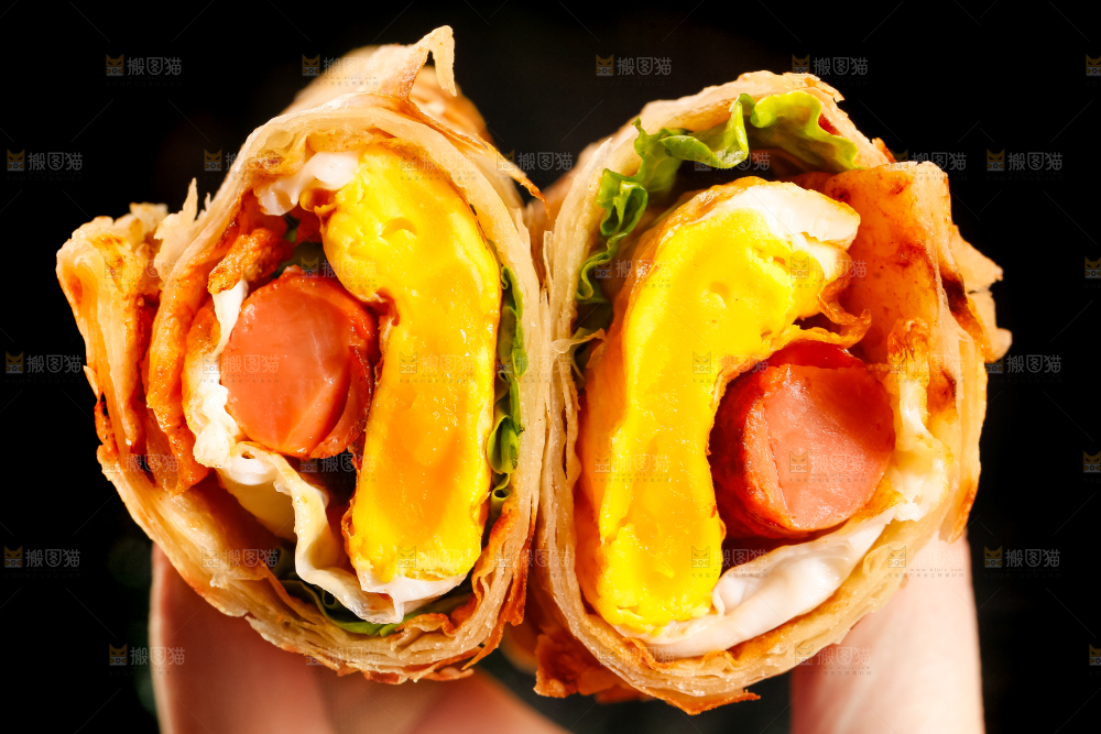 手拿着鸡蛋香肠卷饼