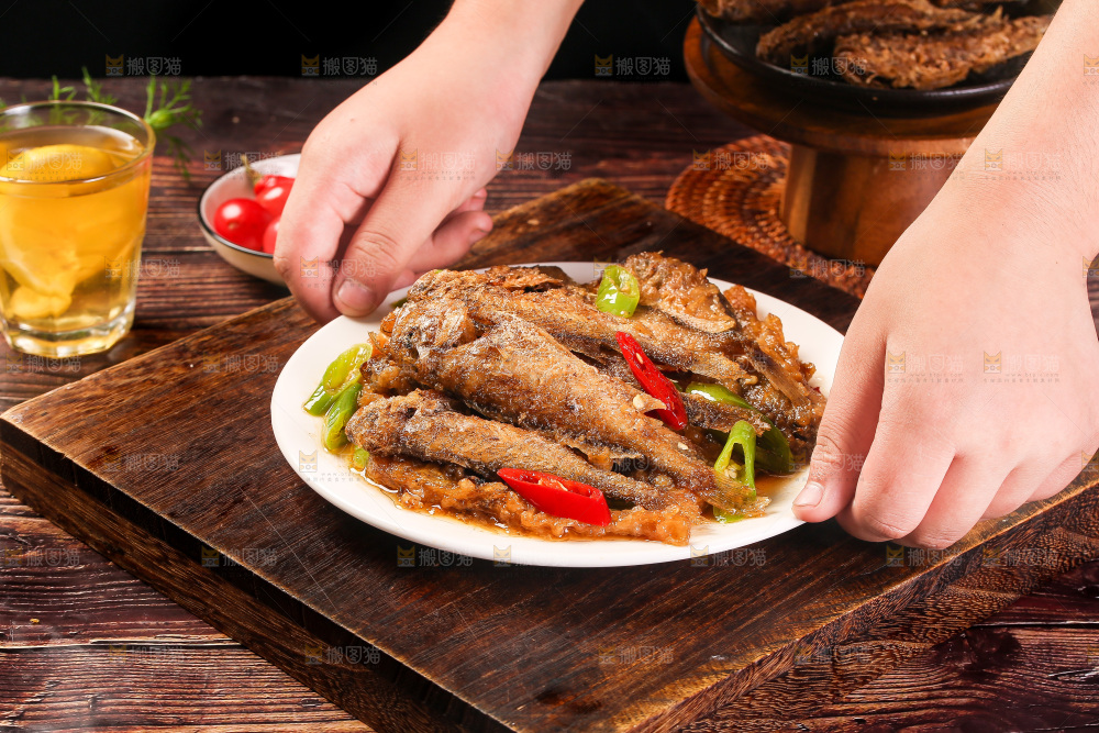 手拿着一盘香酥煎鱼