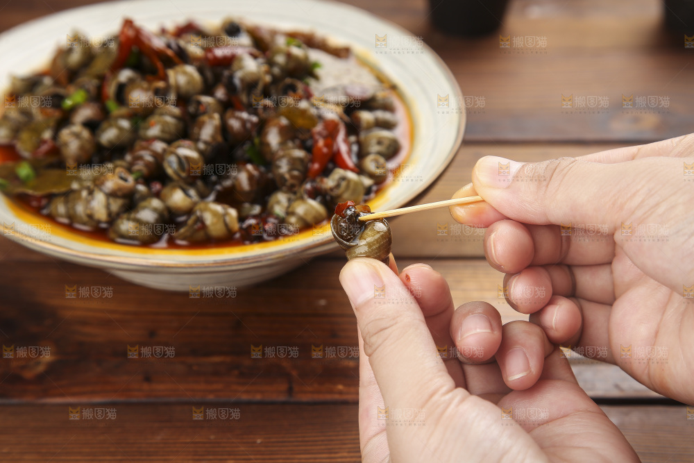 手里拿着牙签挑田螺肉