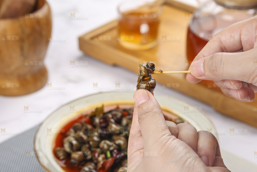手里拿着牙签挑田螺肉