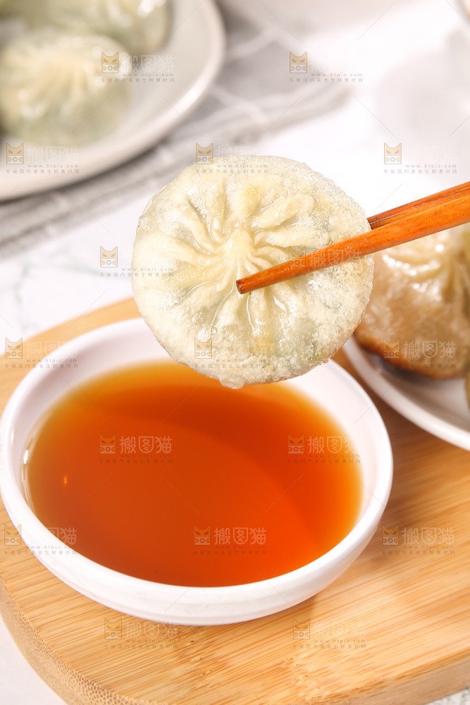 筷子夹着蘸料的小包子