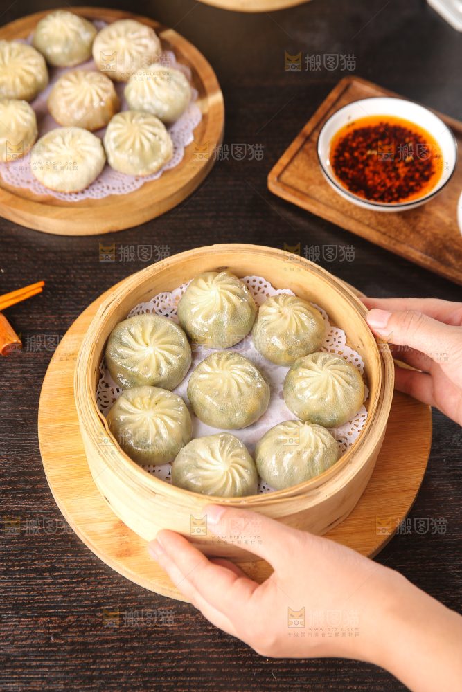 手端着蒸笼里的小包子