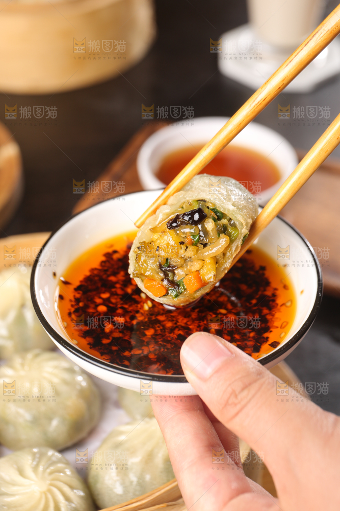 筷子上夹着蘸酱的包子