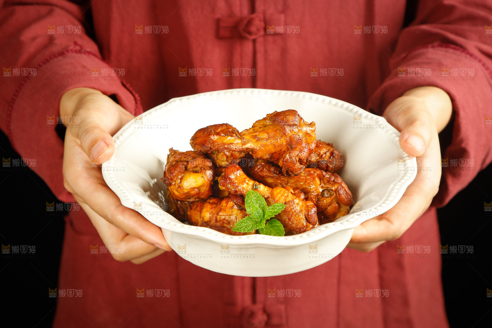 手里端着一盘红烧小鸡腿