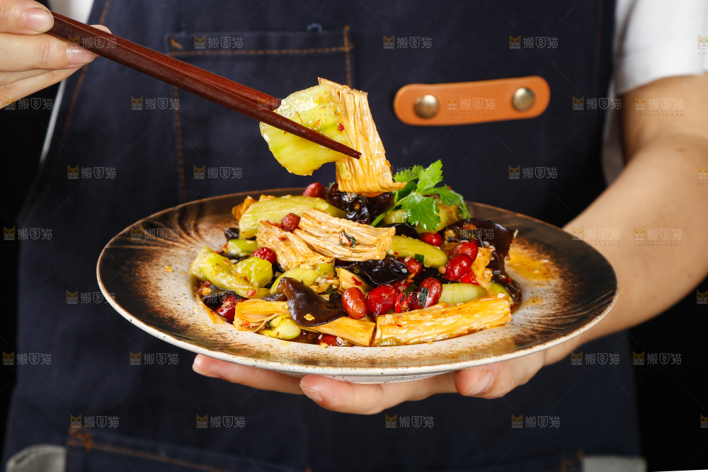 手里端着一盘凉拌腐竹黄瓜