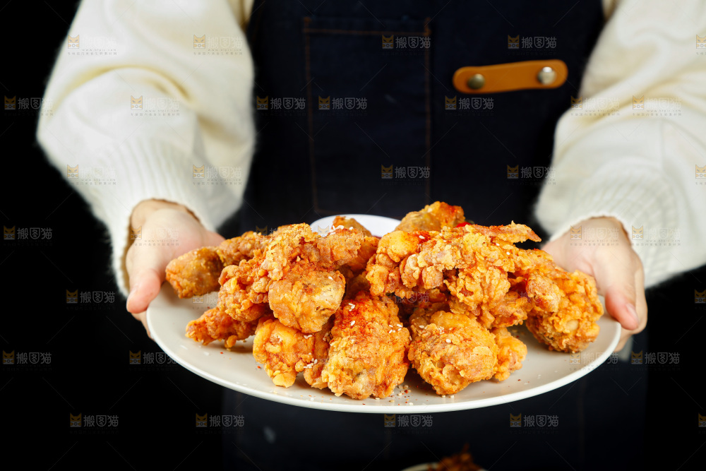 手里端着一盘香酥炸鸡腿