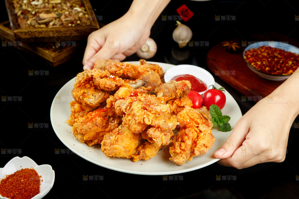 手里端着一盘香酥炸鸡腿