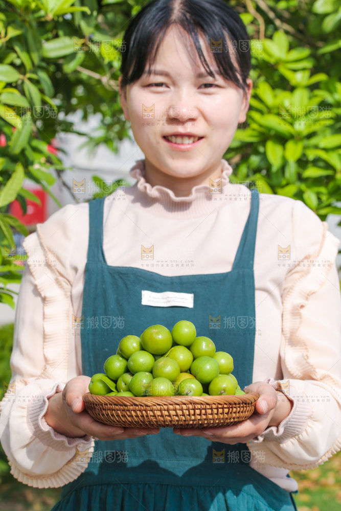 女人手里端着一篮青脆李