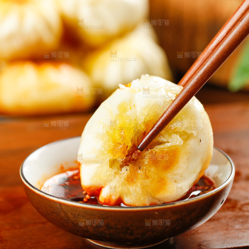 筷子夹着蘸辣椒的煎包