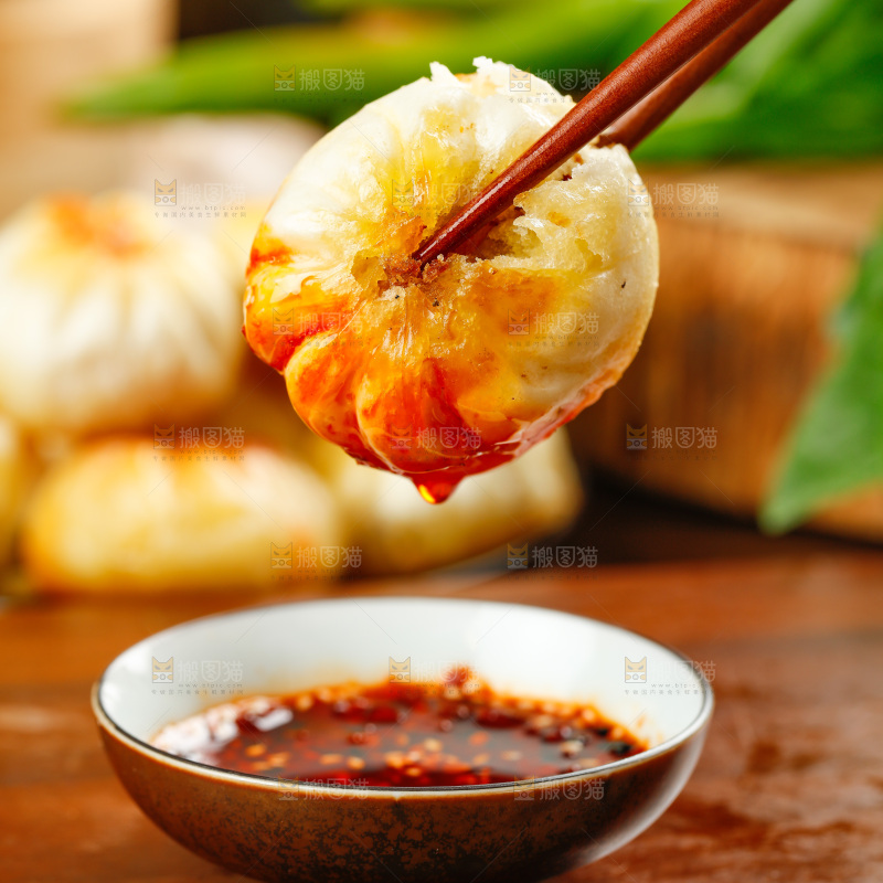 筷子夹着蘸辣椒的煎包