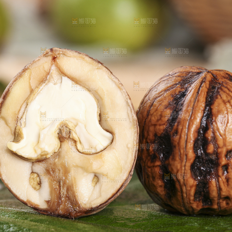 树叶上放着切开的新鲜青皮核桃