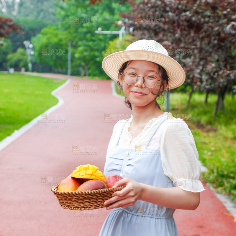 女孩手里端着一篮芒果