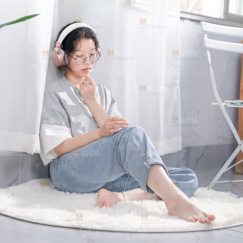 毛毯上坐着一位带耳机的女孩