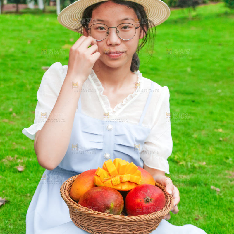 女孩手里端着一篮芒果