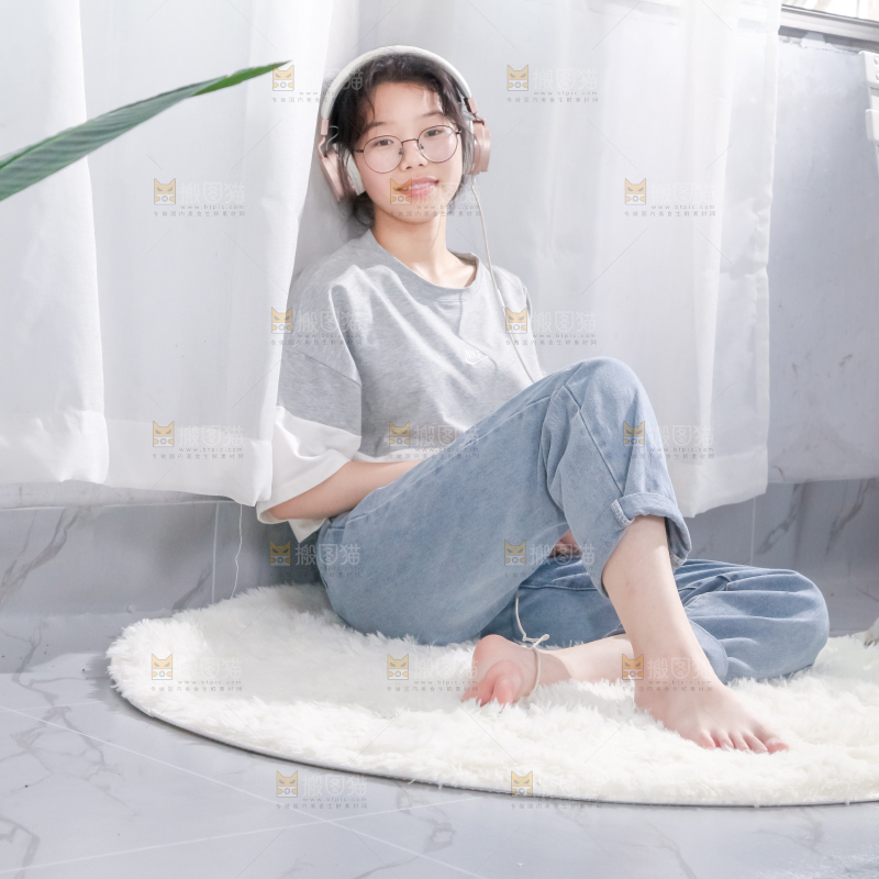 毛毯上坐着一位带耳机的女孩