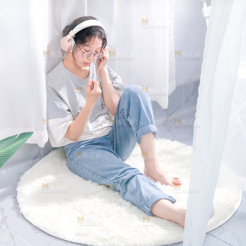 毛毯上坐着一位带耳机的女孩