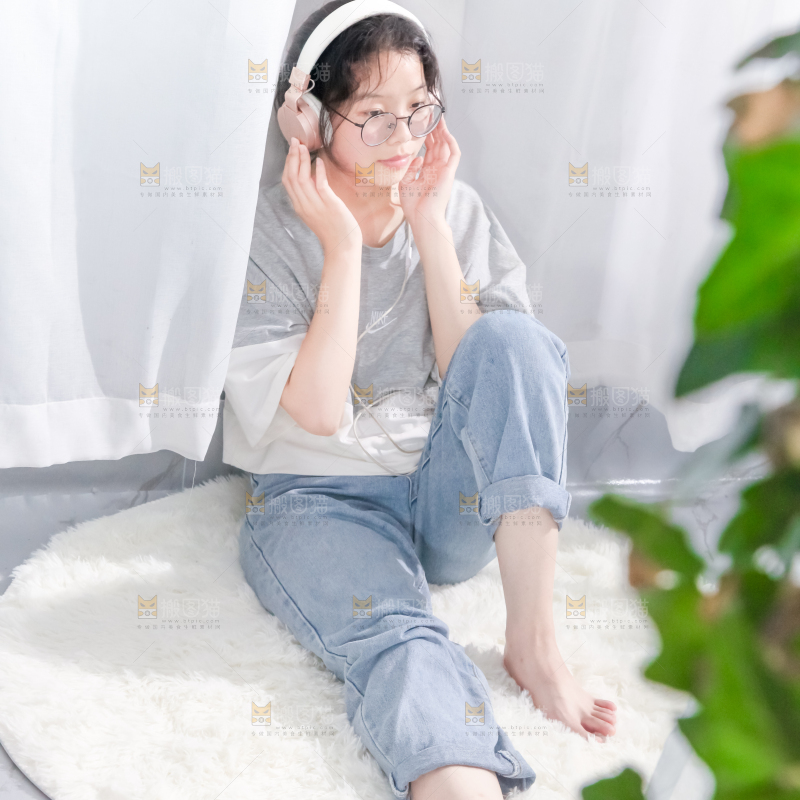 毛毯上坐着一位带耳机的女孩