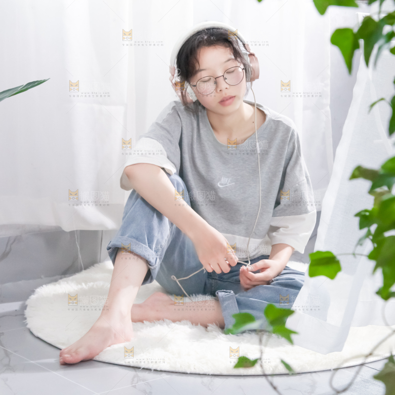 毛毯上坐着一位带耳机的女孩