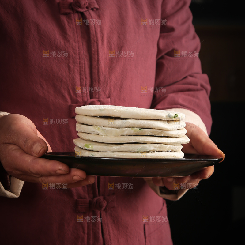 手里端着一盘葱油饼