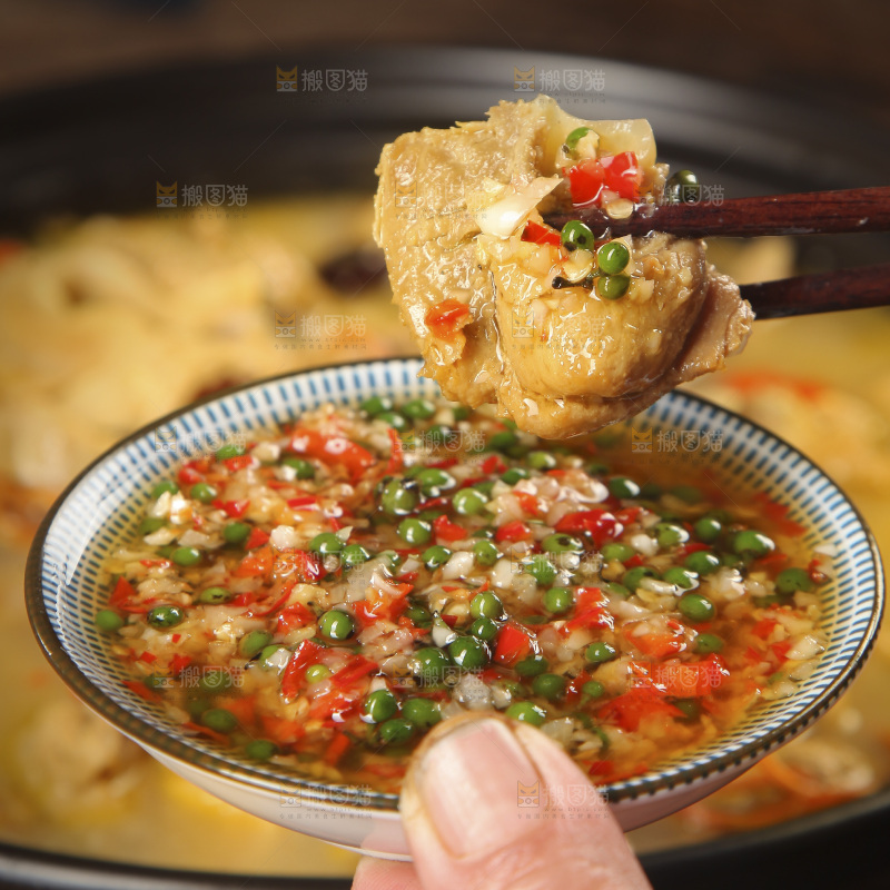 筷子上夹着蘸酱的鸡肉