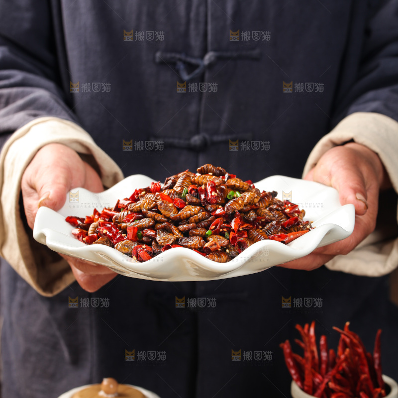 手里端着一盘爆炒蚕蛹