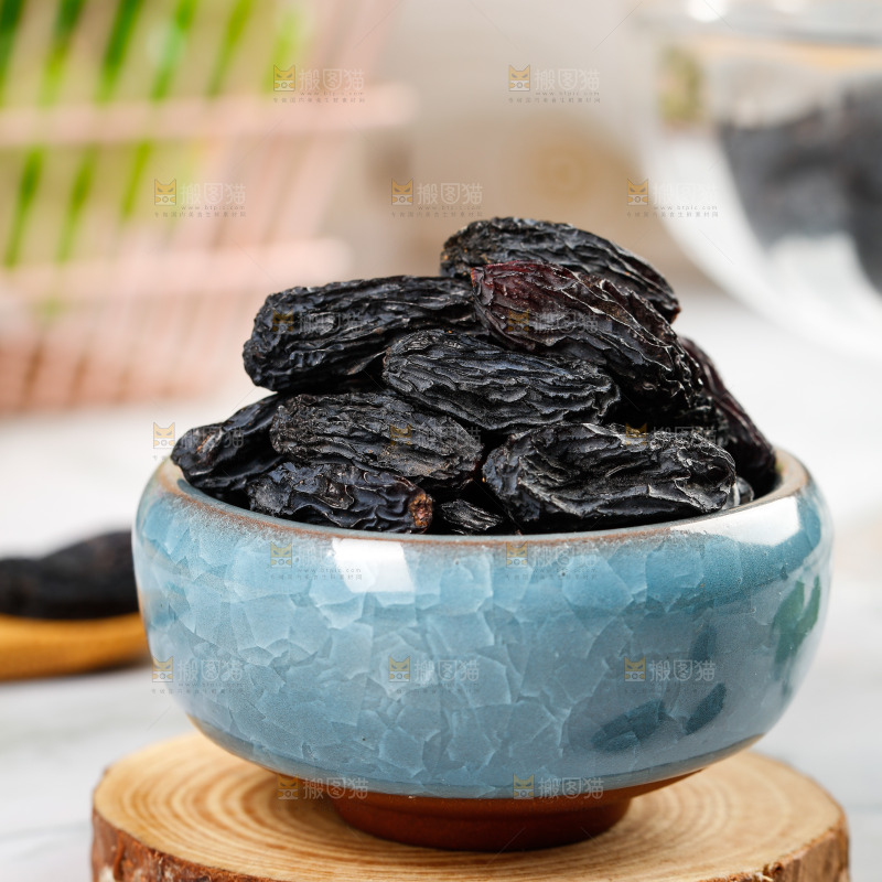木板上放着一碗黑葡萄干