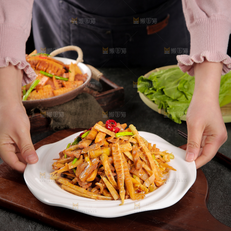 手里端着一盘竹笋烧肉