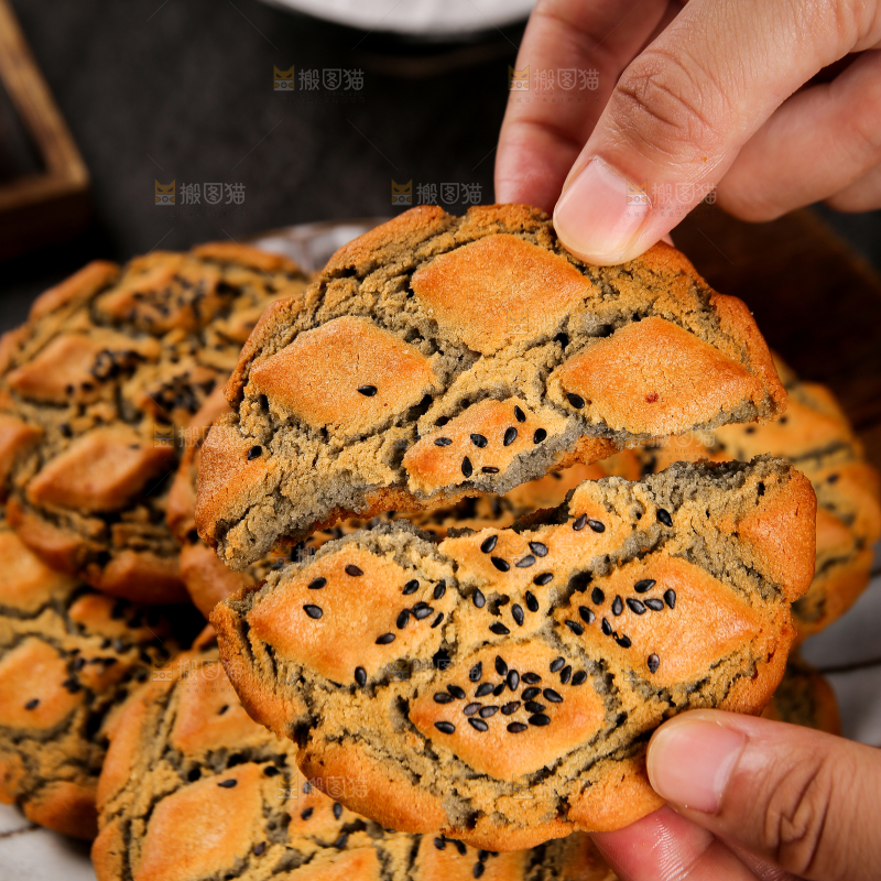 手拿着掰开的芝麻夹心桃酥
