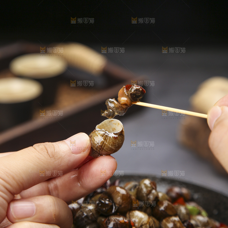 手里拿着牙签挑田螺肉