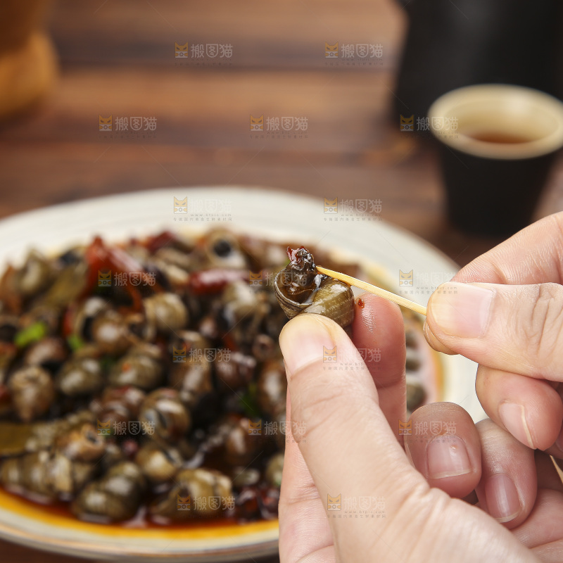 手里拿着牙签挑田螺肉