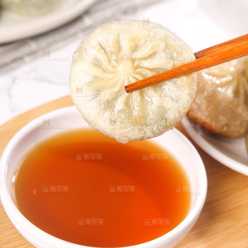 筷子夹着蘸料的小包子