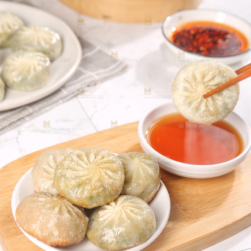 筷子夹着蘸料的小包子