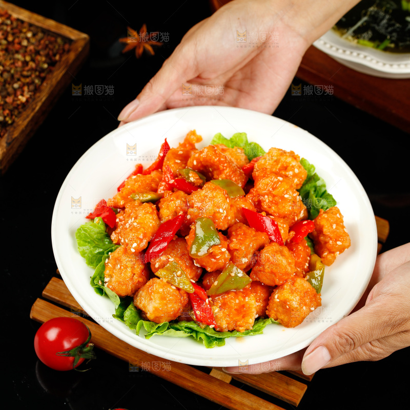手里端着一盘香辣咕咾肉