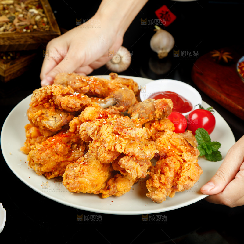 手里端着一盘香酥炸鸡腿